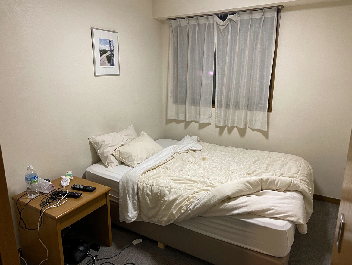 A dim hotel room photographed in flat, uneven light